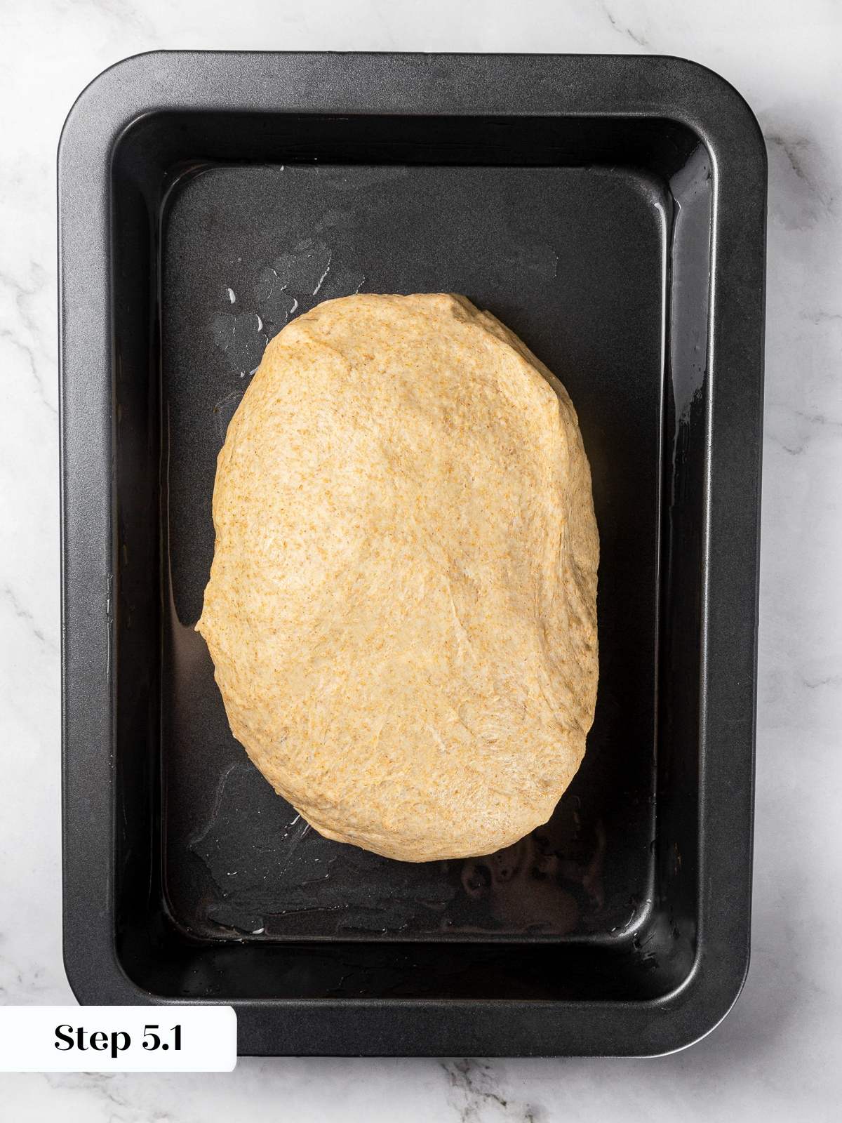 Focaccia dough resting in oiled pan during bulk proof before folding.