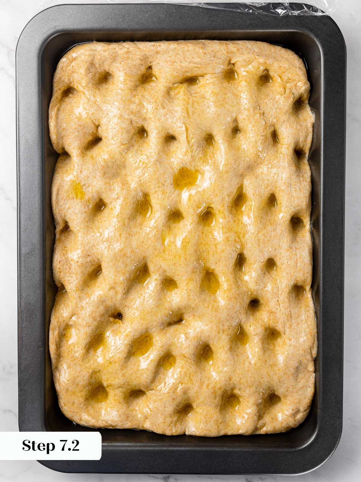 Dimpled focaccia dough with fingertips to create classic olive oil pockets.