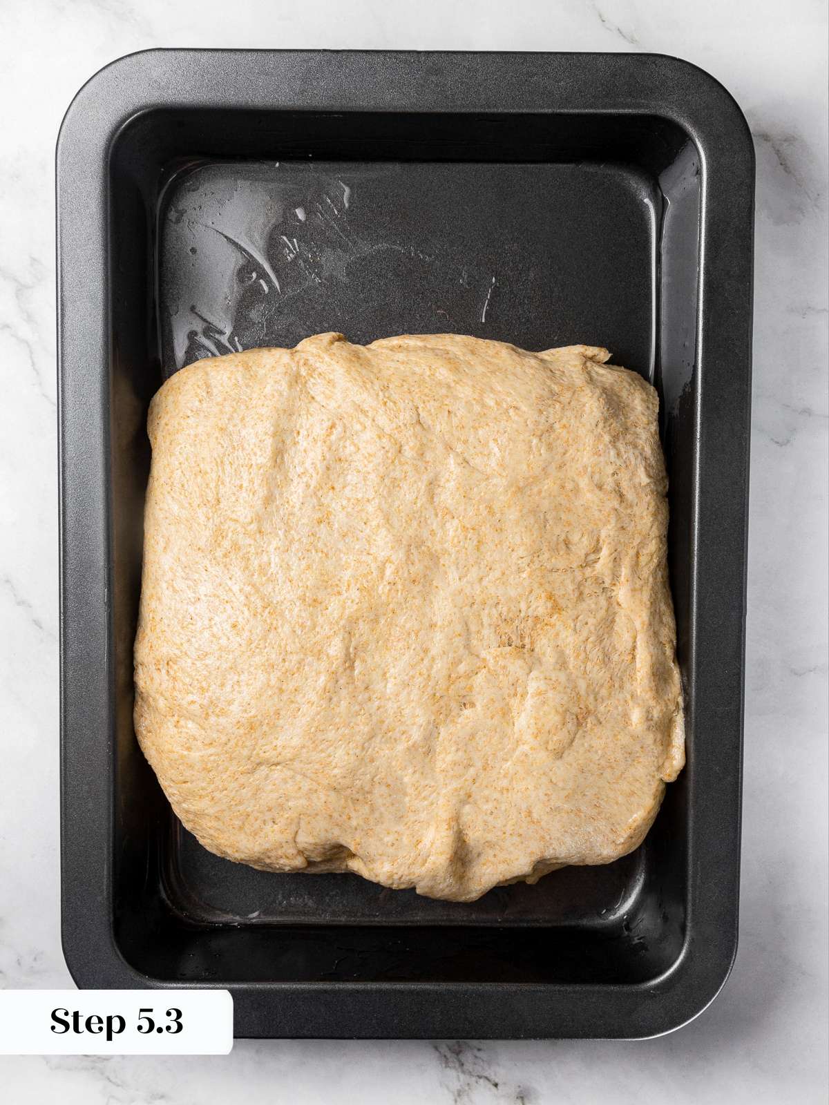 Folded focaccia dough forming square shape after envelope folds.