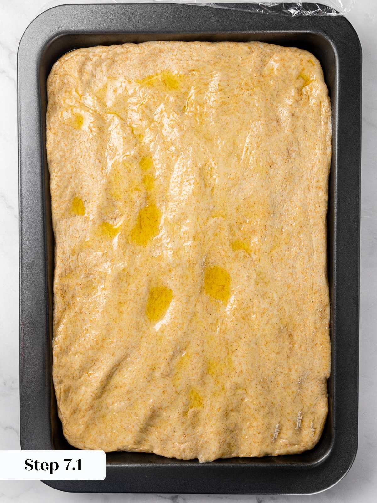 Olive oil drizzled over stretched focaccia dough before dimpling.