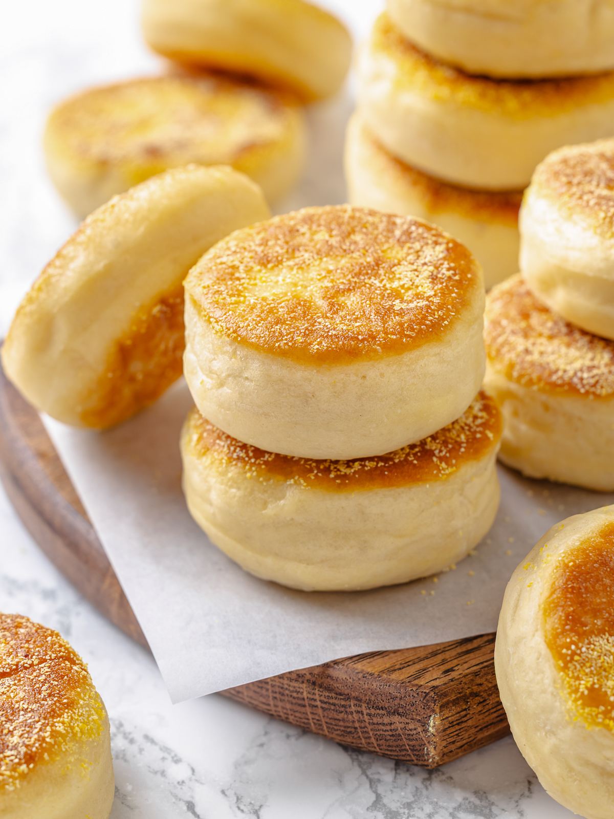 Group of English muffins stacked together showing uniform shape and lightly golden tops.