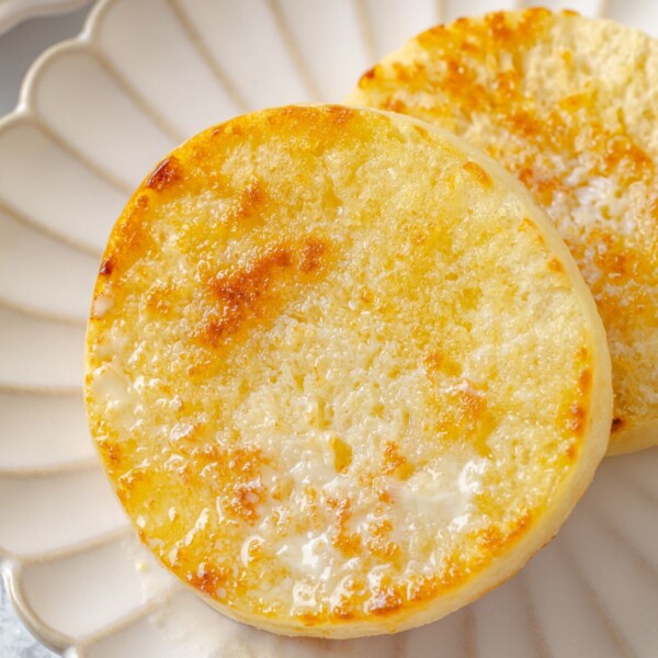 Warm English muffin with butter melting into interior pockets and soaking into crumb.