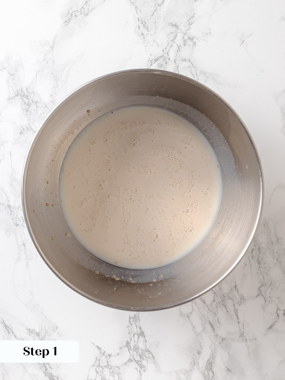 Yeast blooming in warm milk with bubbles forming across surface indicating active fermentation.