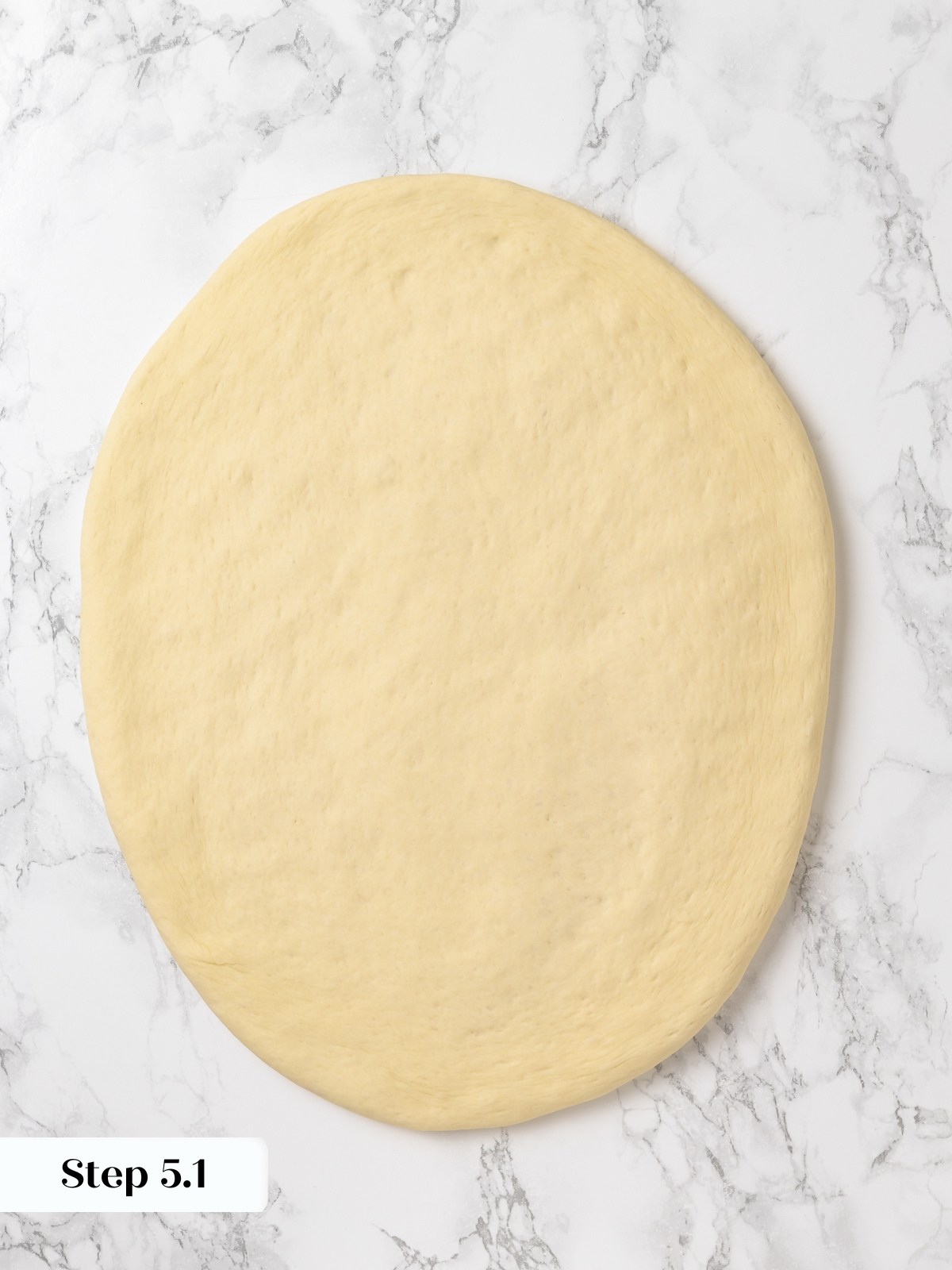 Dough pressed flat on countertop to even thickness before cutting into rounds.