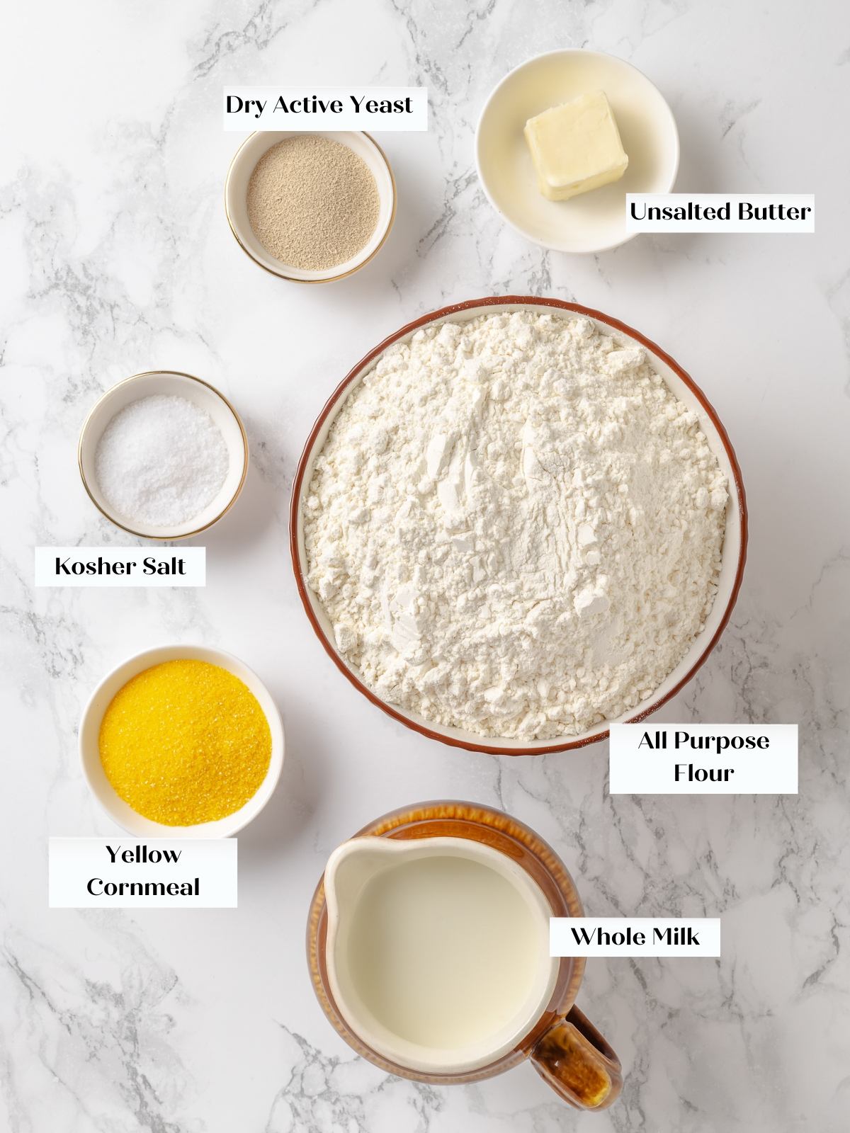 Measured ingredients arranged on countertop including flour, milk, butter, yeast, salt, and cornmeal.