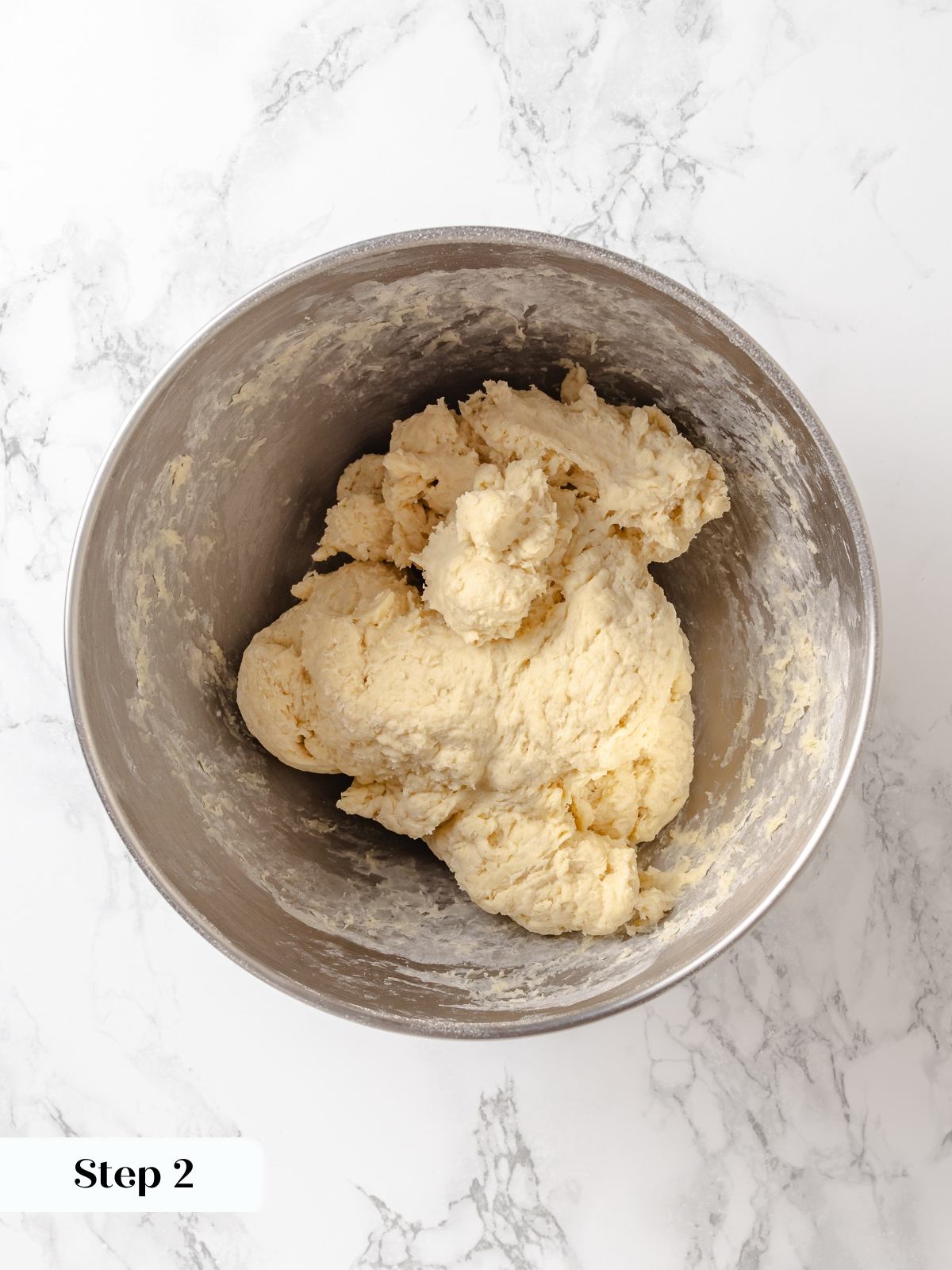 Early stage dough appearing uneven and slightly sticky before gluten fully develops during mixing.