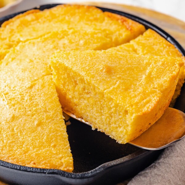 Slice of sourdough cornbread lifted with pie server showing clean cut and tender crumb.