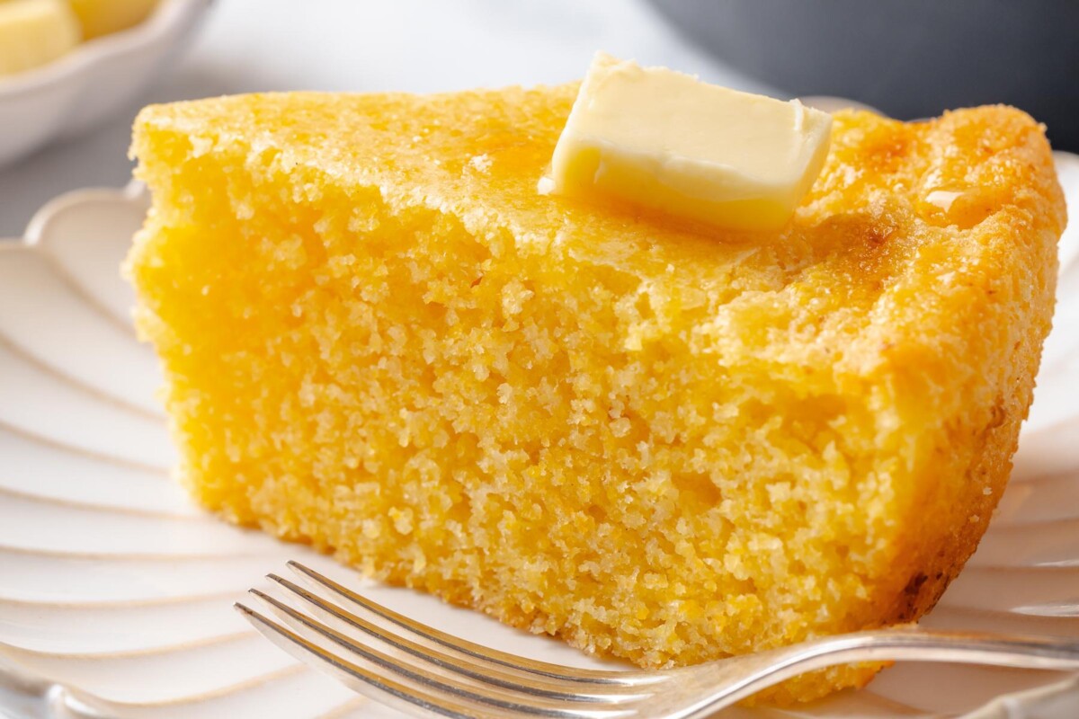Triangular wedge of cornbread with crisp edges and soft, tender interior crumb.