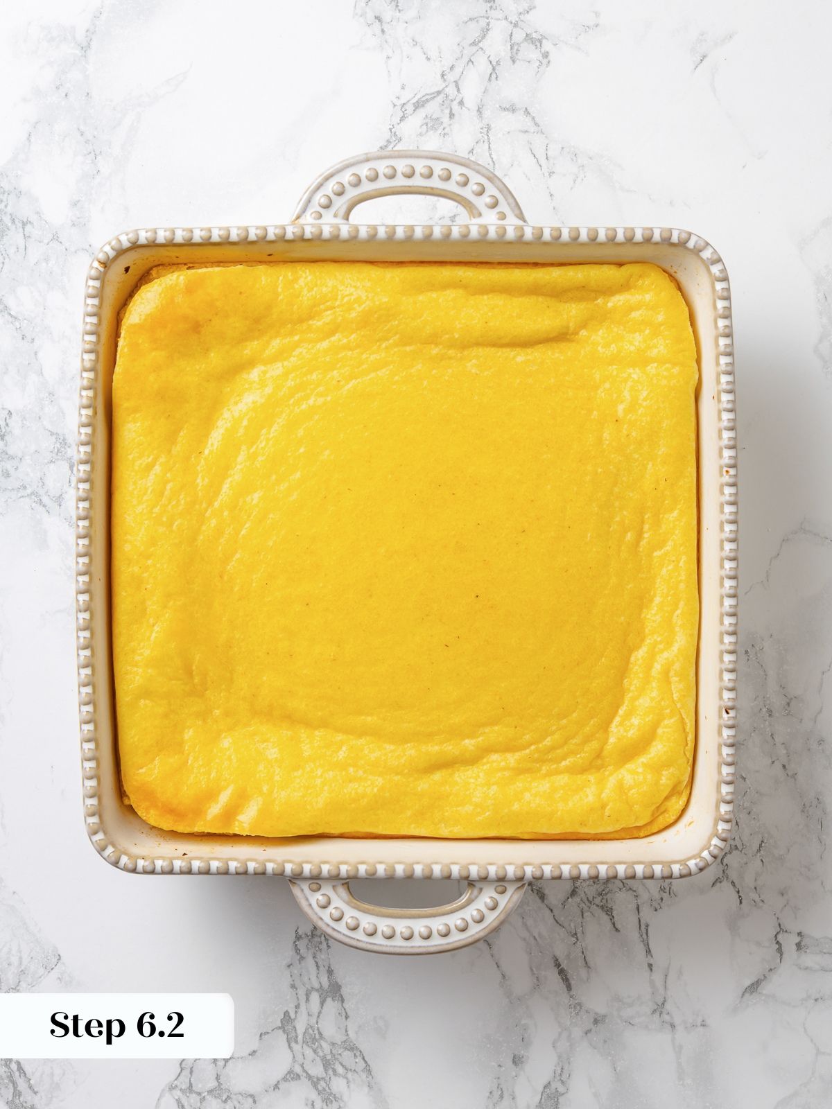 Spoon bread baked in dish with puffed center and lightly golden surface just out of oven.