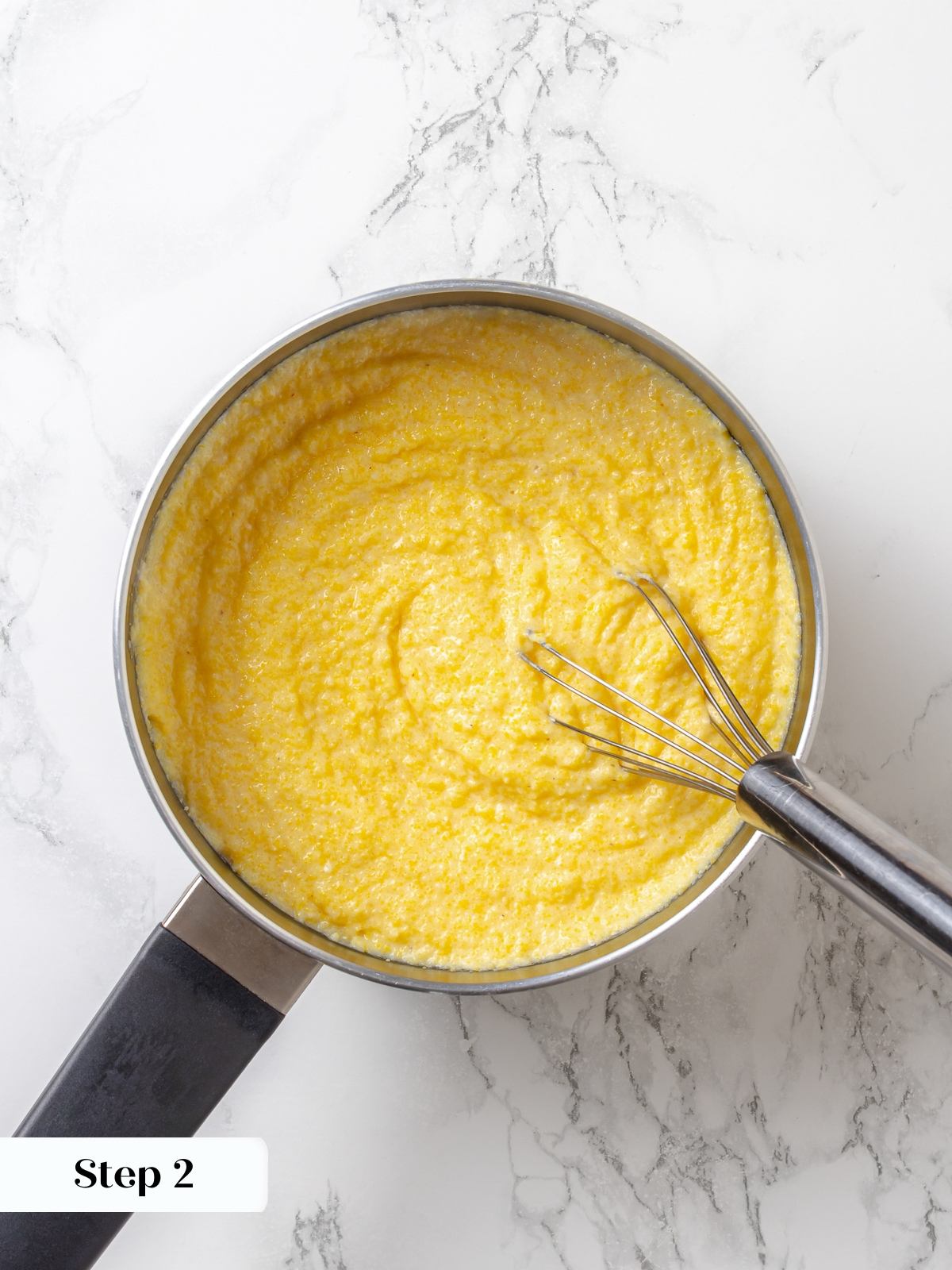 Cornmeal and milk cooking together in pot, thickening into smooth, creamy mixture.