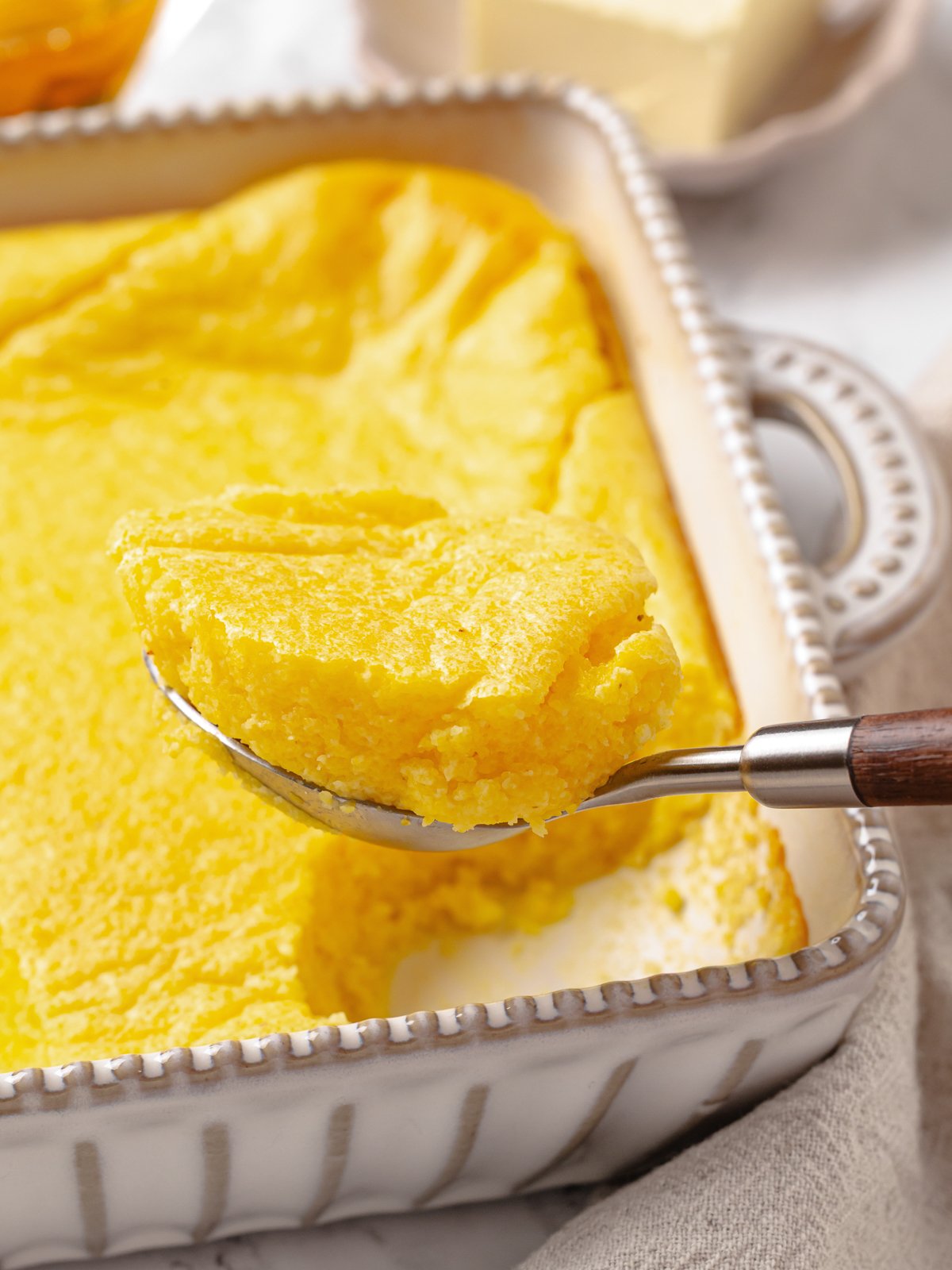 Spoonful of warm spoon bread ready to serve, highlighting soft and fluffy consistency.