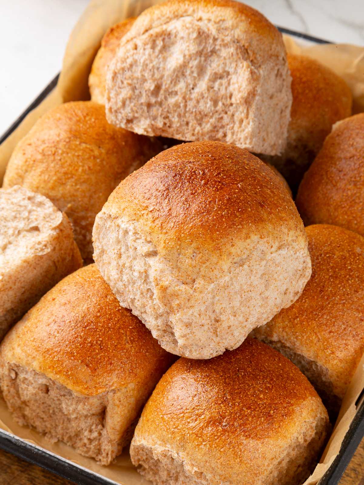 Several whole wheat sourdough rolls displayed together showing soft texture and golden crust.