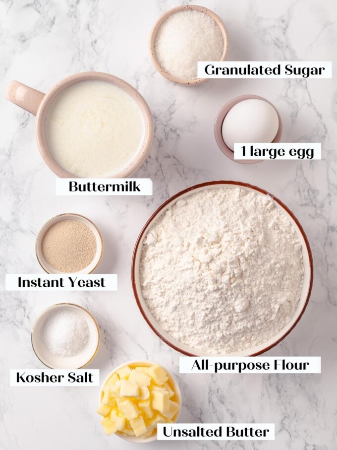 Ingredients arranged on marble for buttermilk bread including flour, butter cubes, and buttermilk.