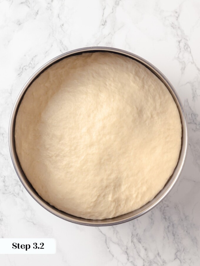 Buttermilk bread dough doubled in size after first proof in stainless steel bowl.