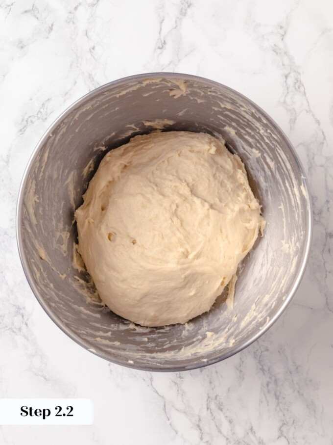 Smooth buttermilk dough kneaded to windowpane stage inside stainless steel mixer bowl.