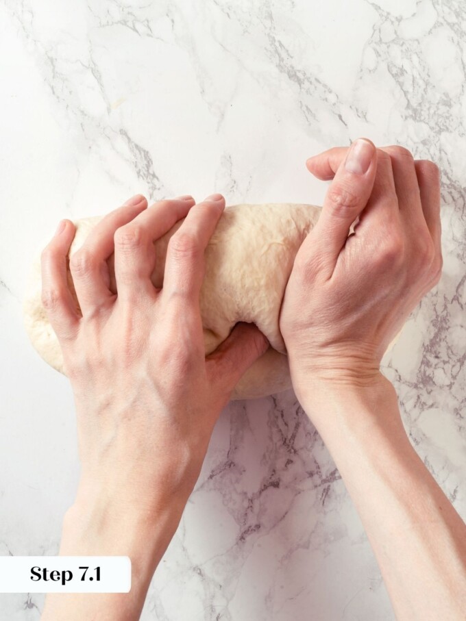 Two hands sealing buttermilk dough log with thumb fold technique on marble counter.