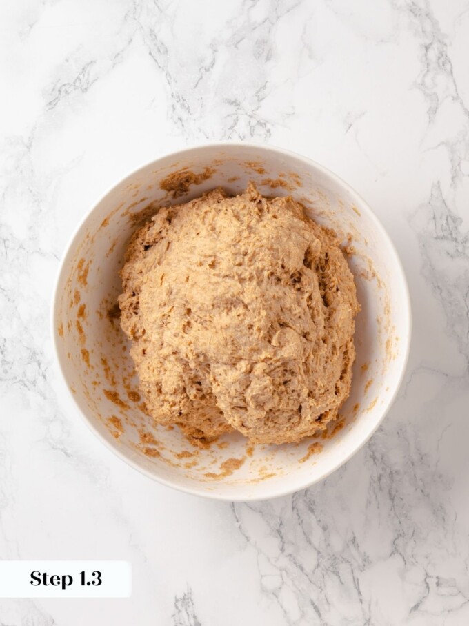 Whole wheat dough nearly combined in white ceramic bowl with rough textured surface.