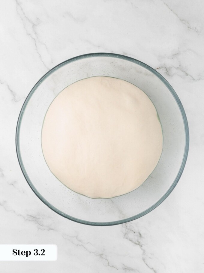 Sourdough English muffin dough slightly puffed in a glass bowl after thirty minutes of bulk proofing.