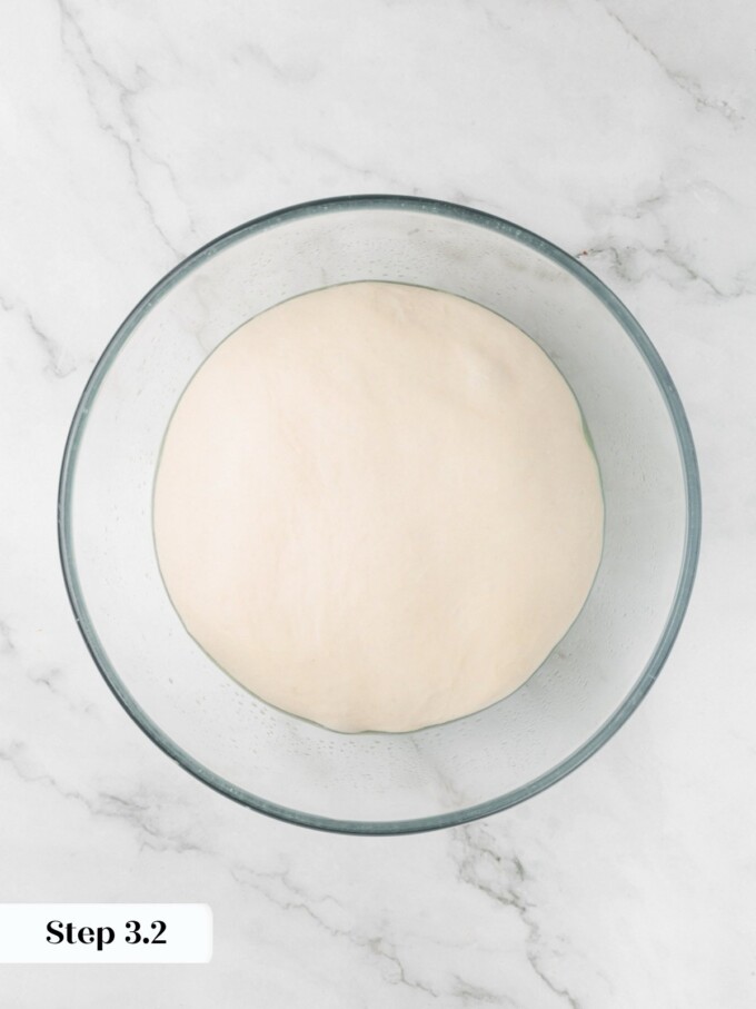 Sourdough English muffin dough slightly puffed in a glass bowl after thirty minutes of bulk proofing.