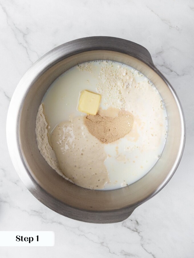 Whole milk, butter, flour, sourdough starter, and yeast combined in a stainless steel stand mixer bowl.