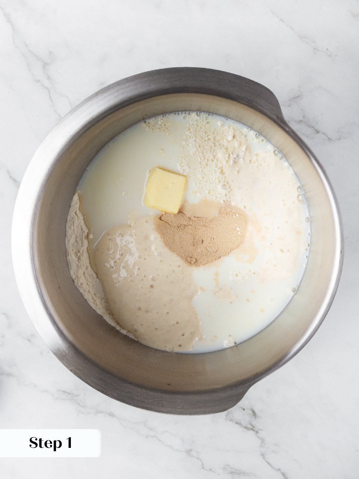 Whole milk, butter, flour, sourdough starter, and yeast combined in a stainless steel stand mixer bowl.