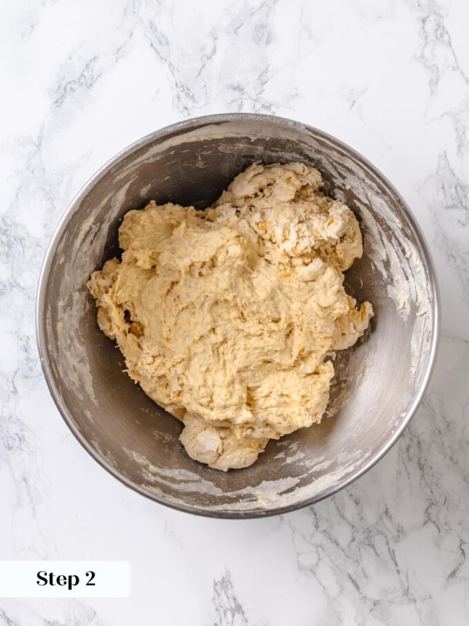 Rough shaggy pretzel dough freshly combined inside a stainless steel mixer bowl after low speed mixing.