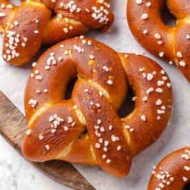 Single salted pretzel with glossy dark crust framed by surrounding pretzels in a tight square arrangement.