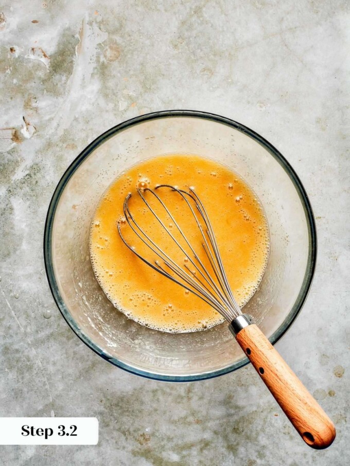 Smoothly emulsified wet ingredients for strawberry bread, fully whisked and pale orange in a glass bowl.