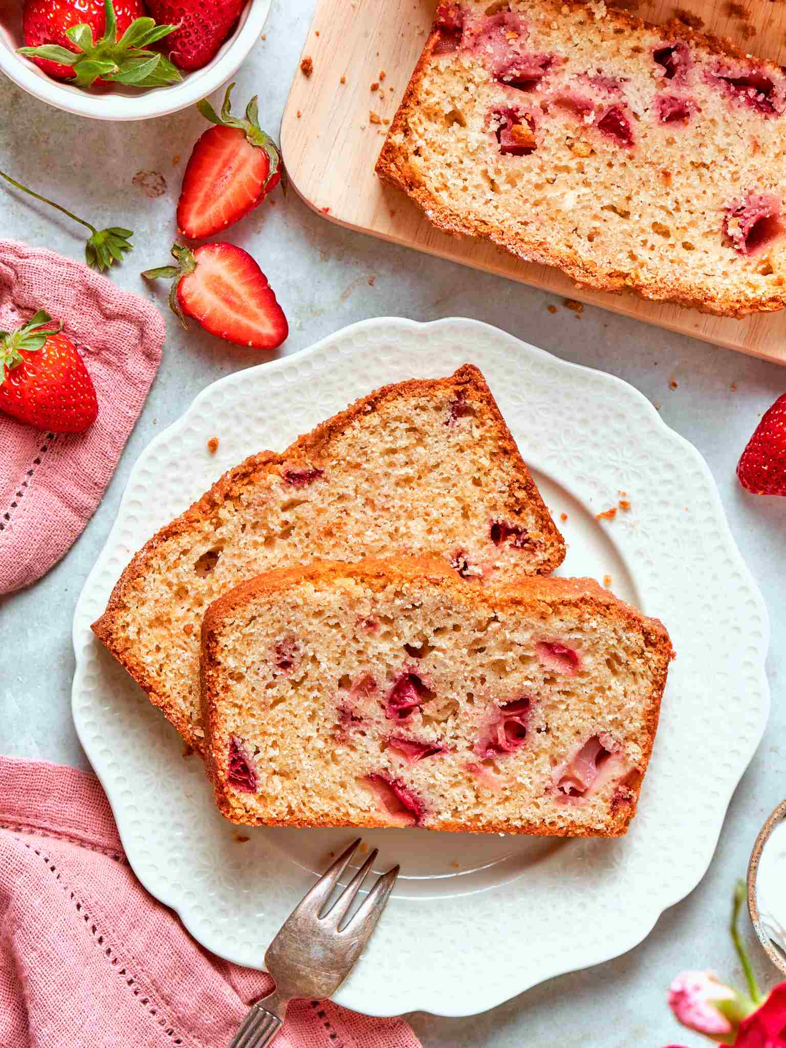 Plated strawberry bread slice with a small antique fork and bright red berries in the frame.