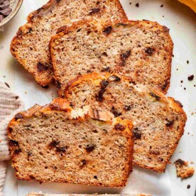 Stacked slices of vegan banana bread revealing a soft, chocolate-studded crumb in detail.