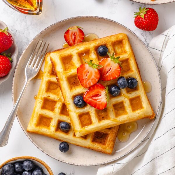 Crisp belgian waffles hold their texture under fresh berries and syrup for a weekend brunch.