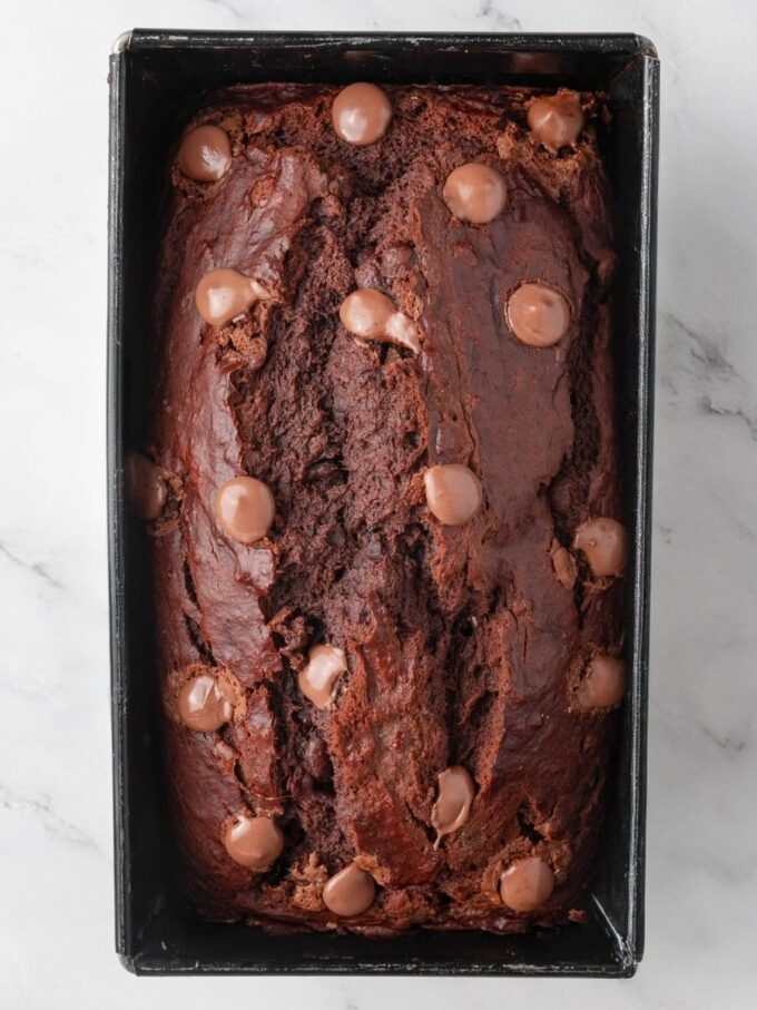Resting briefly in the pan lets gluten free chocolate banana bread set before lifting and slicing.