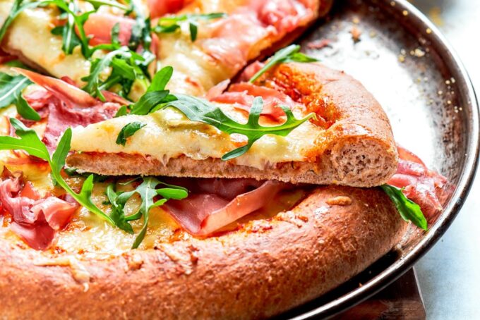 This wide view frames the chewy whole wheat pizza dough crust ready for serving and slicing.