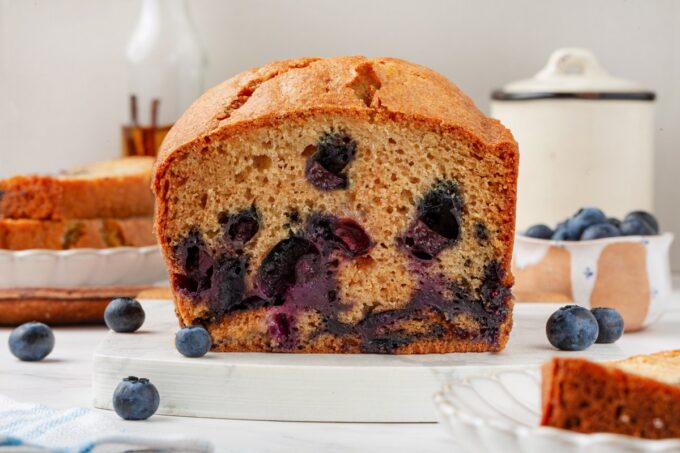 Landscape framing fits in-post banners while showing berries suspended through the blueberry bread crumb.