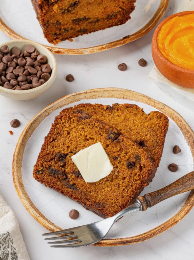 Butter melting on a warm slice shows the cozy way to serve chocolate chip pumpkin bread.