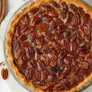 Toasted pecan halves crown the pumpkin pecan pie, hiding the spiced pumpkin layer waiting beneath.