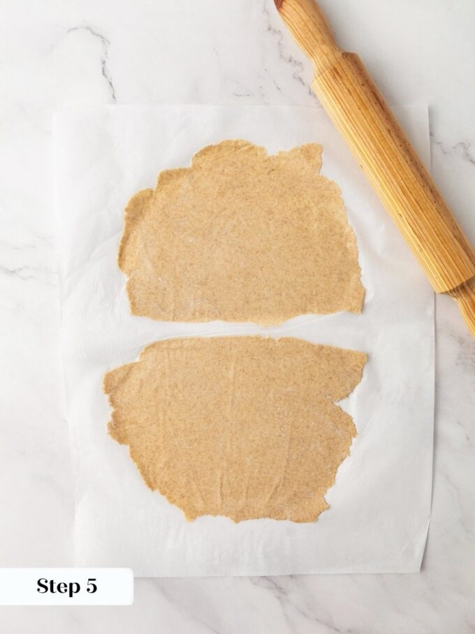 Halving the sheet and rolling again is how sourdough crispbread reaches its translucent shatter-crisp thinness.