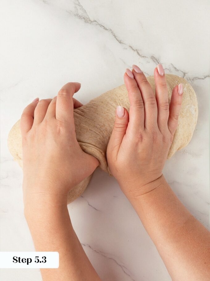 The first thumb fold never closes the log; a second pass finishes sourdough rye bread.