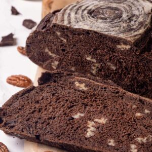 Square-framed sliced chocolate sourdough bread reveals the pecan and chocolate pockets defining its chewy open interior.