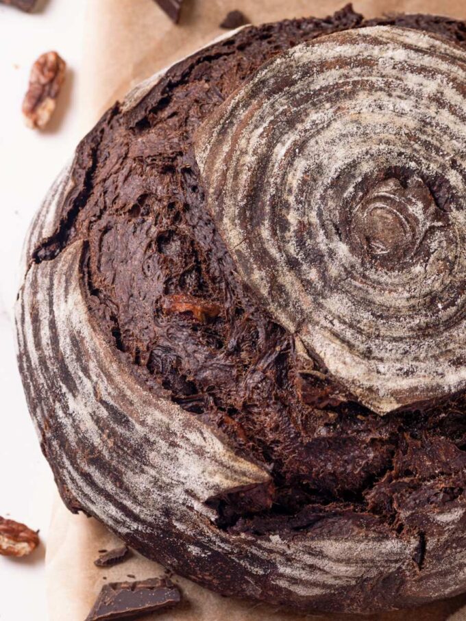 An angled top view captures how the banneton spiral crowns this chocolate sourdough bread's crackly crust.