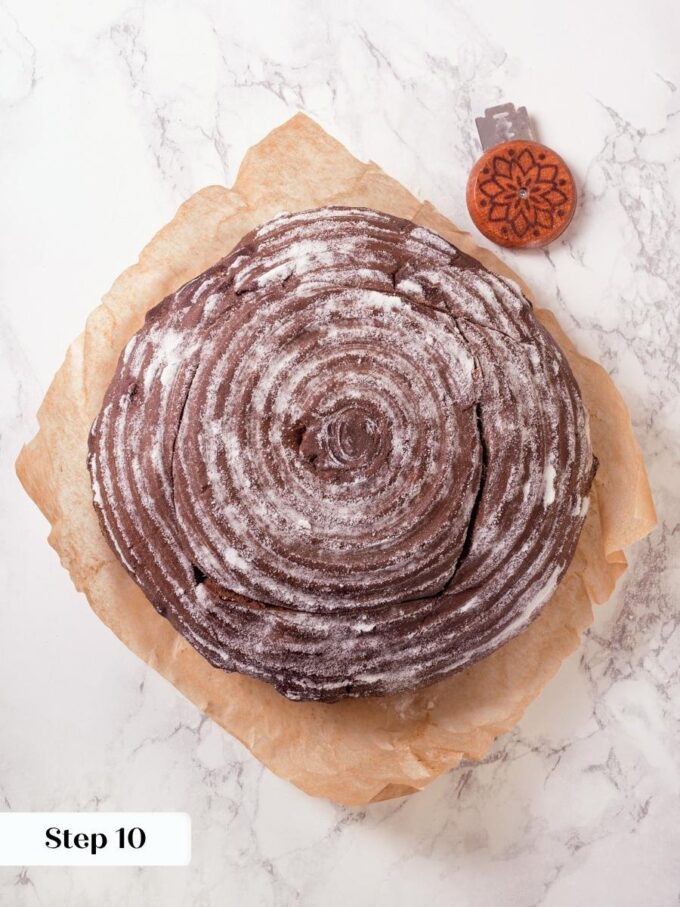 A banneton spiral imprint previews the dramatic crackled crust that will form on chocolate sourdough bread.