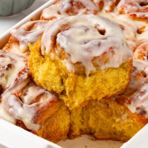 Lifting a roll free reveals the orange crumb that sets these pumpkin cinnamon rolls apart.