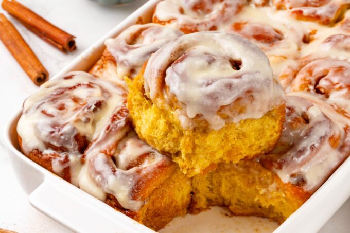 Landscape framing keeps the orange crumb visible, so pumpkin cinnamon rolls read clearly at small sizes.