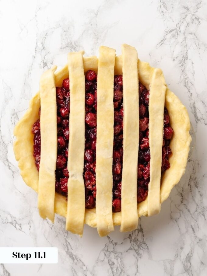 Building a lattice top for sour cherry pie starts with evenly spaced strips across the filling.